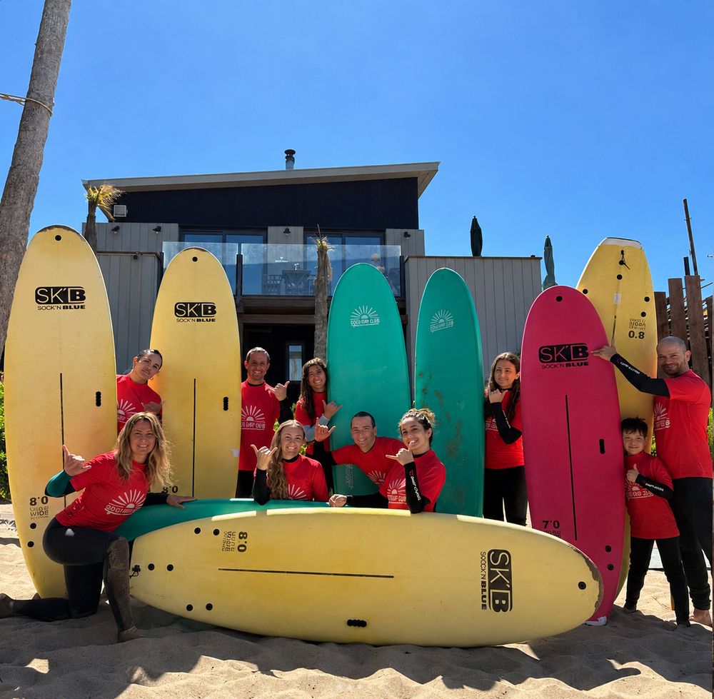 Grupo de alumnos con remeras de Coco Surf Club y sus tablas